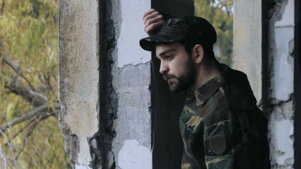 Joven militar vestido está llorando y mirando hacia fuera de su refugio: soldado — Vídeo de stock