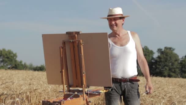 Painter with an easel in the middle of a cornfield — Stock Video