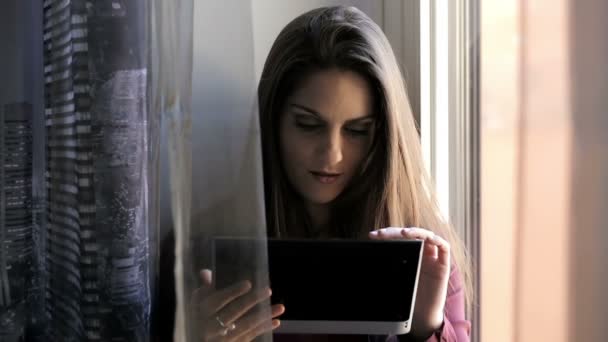 Young woman using tablet near window: computer, browse, web, cute, standing — Stock Video