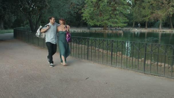 Young couple having fun in a park making jokes after shopping: shopping bag — Stock video