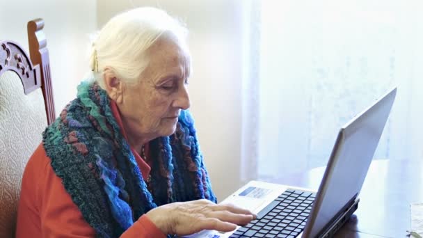 Oude vrouw met behulp van personal computer thuis — Stockvideo