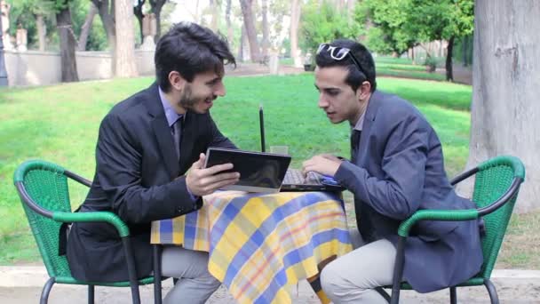 Two businessmen using tablet and laptop during an informal meeting in a bar — Stock Video