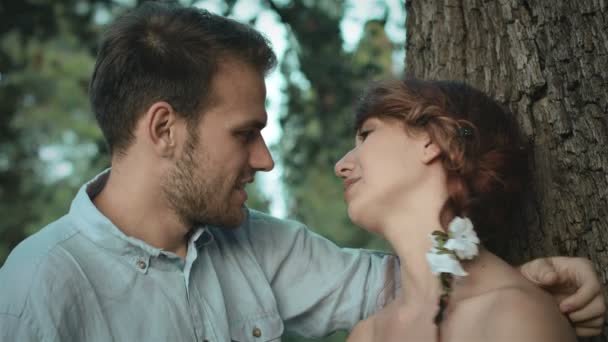 Jovem casal conversando e beijando perto de uma árvore em um jardim público: parque, ao ar livre — Vídeo de Stock