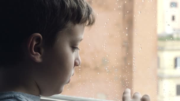 Szomorú és magányos gyermek állt az ablakon kinézve az eső — Stock videók