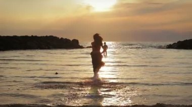 aşık giyimli kadın erkeğini için deniz - hugs ve öper - gün batımına doğru çalışır.