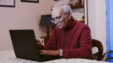 yaşlı adam evde dizüstü bilgisayar kullanan: emekli adam öğrenmek bir pc kullanmak