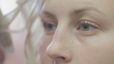 Sarışın bir kadının, bukleleri yapmasına yardım eden bir arkadaşıyla yakın çekimi.