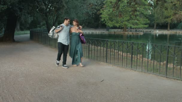 Young couple in lovee inside a park is making jokes after shopping — Stockvideo