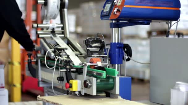 Worker puts tubes of cream in the machine for label — Stock Video