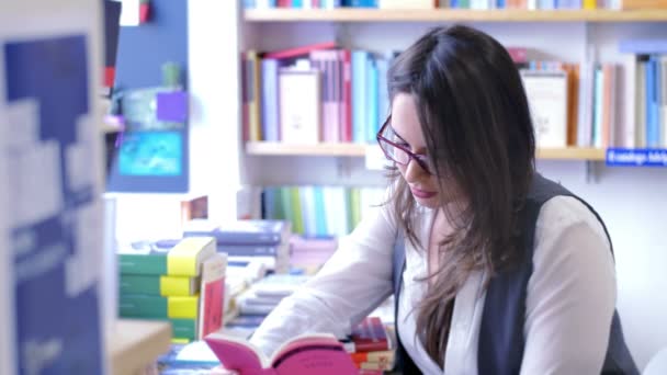 Mujer leyendo en la librería — Vídeos de Stock