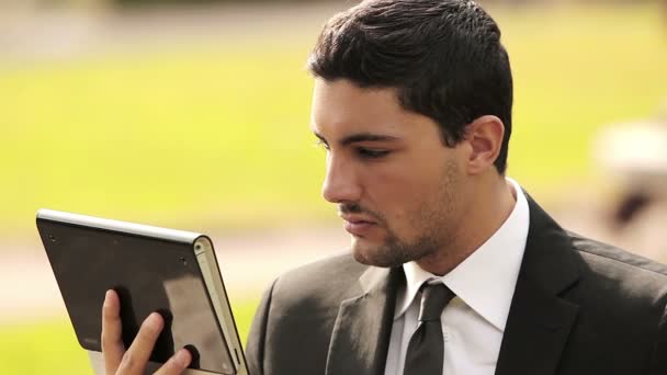 Homem de negócios usando tablet digital no parque — Vídeo de Stock