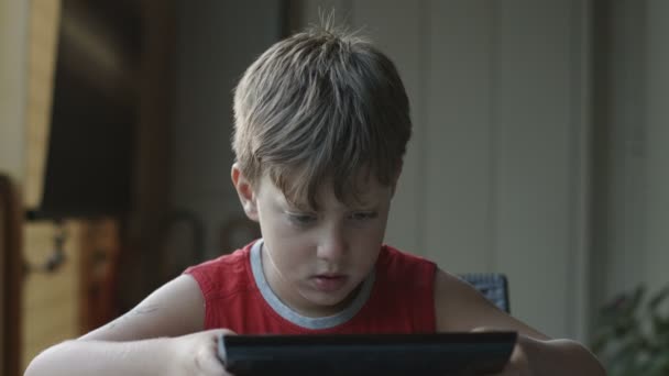 Criança bonita está usando um computador tablet na mesa: jogo, diversão, aprendizagem — Vídeo de Stock