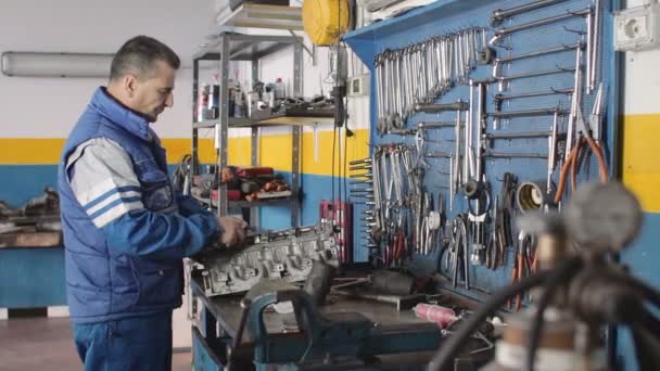 Автомеханик, ремонтирующий часть автомобильного двигателя — стоковое видео