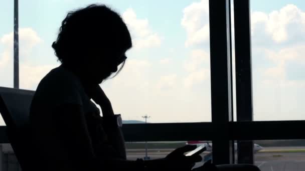 Nő vár fly a reptérre, és használ smartphone — Stock videók