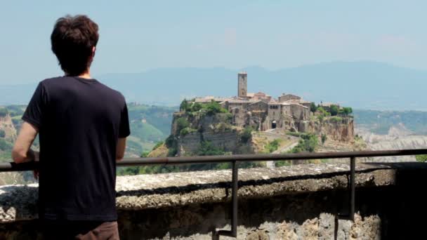 Мужчина смотрит на красивую итальянскую деревню — стоковое видео