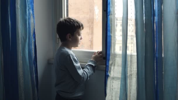 Triste enfant regardant par la fenêtre dans un jour de pluie — Video