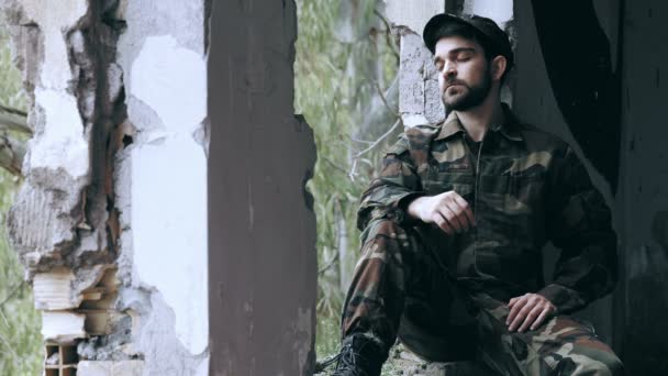 Fundersam soldat sitter ensam i en gammal byggnad — Stockvideo