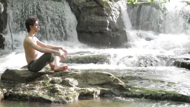 Young boy in meditation near the river — Stock Video