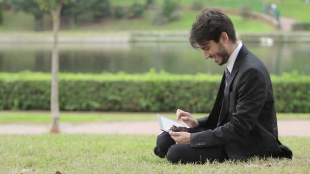 Homem de negócios usando tablet digital no parque — Vídeo de Stock