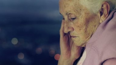 Yalnız ve depresyonda yaşlı kadın kadın gece pencereden dışarı bakarak