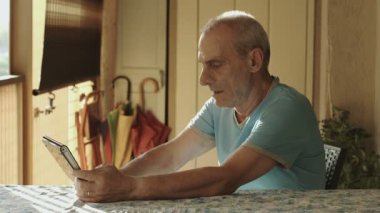 yaşlı adam evde tablet bilgisayar kullanıyor: yaşlı, teknoloji, internet