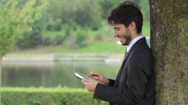 Tablet Pc dışında bir parkın kullanan mutlu iş genç adam