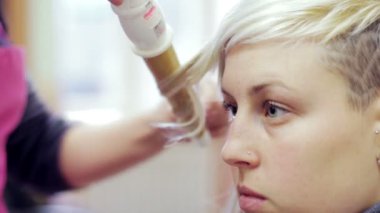 Bir kuaför geçit töreninden önce bir mankene bukleler yapar.