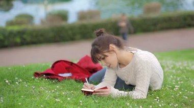 güzel genç kadın bir günlük açık havada parkta yazıyor: