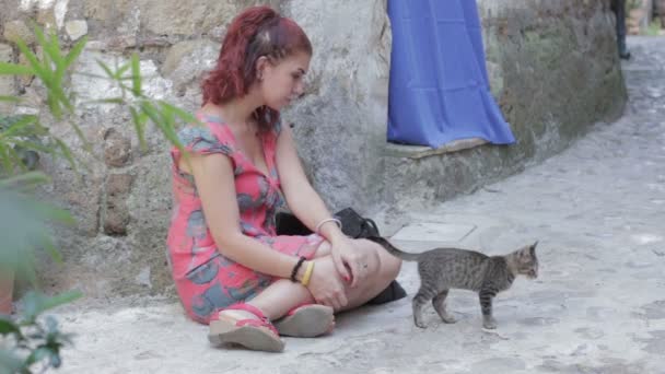 Woman sitting on the street and looking on kitten — Stock Video