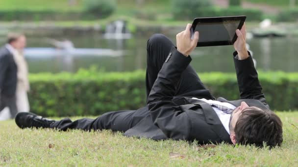 Jonge zakenman werken met tablet pc buiten in park — Stockvideo