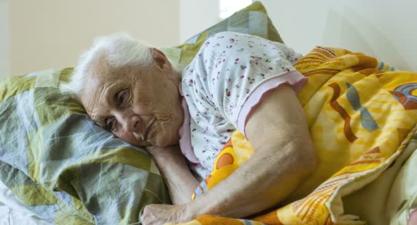 Anciana descansa muy cansada acostada en la cama — Vídeos de Stock