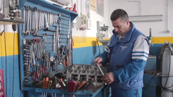 Mecánico de automóviles reparando una parte de un motor de coche — Vídeo de stock