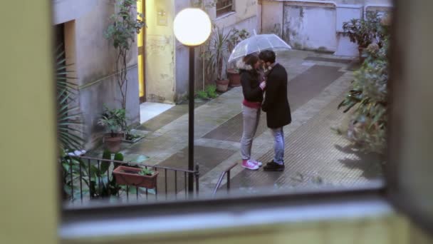 Jeune homme et une femme embrasser sous un parapluie sous la pluie — Video