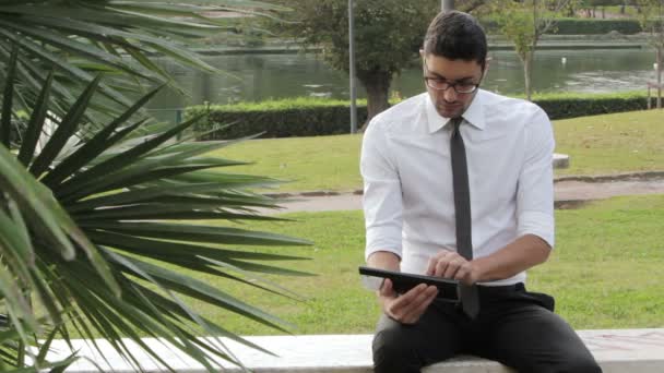 Geschäftsmann im Park sitzt mit Tablet auf Bank — Stockvideo