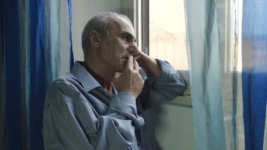 üzgün ihtiyar pencerenin sigara içiyor