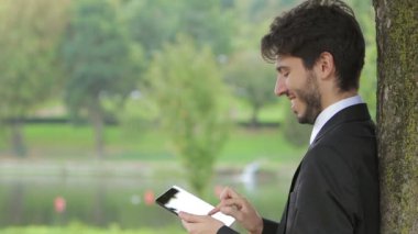 genç işadamı parkta tablet ile çalışma