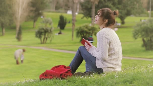 Hermosa joven está escribiendo un diario al aire libre en el parque : — Vídeos de Stock