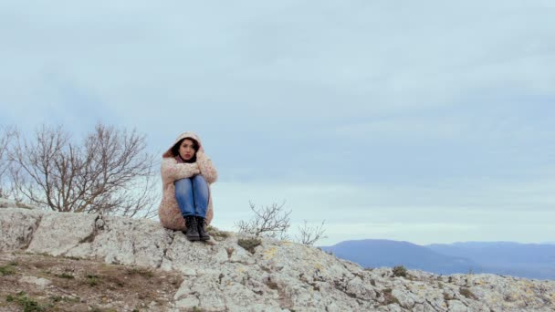 Одинокая медитативная девушка на вершине ветреного холма — стоковое видео
