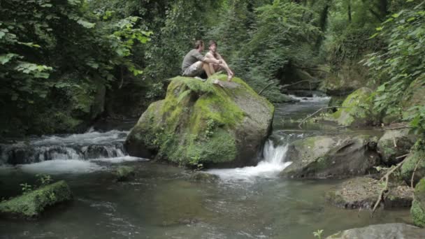 Zwei Jungen sitzen auf einem Felsen im Fluss: Liebe, schwul, homosexuell — Stockvideo