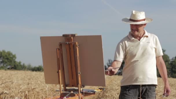 Painter in the middle of a cornfield paints a beautiful landscape, canvas, easel — Stock Video