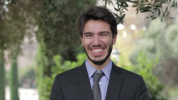 Портрет гарного бізнесмена, який посміхається на камеру в природному середовищі — стокове відео