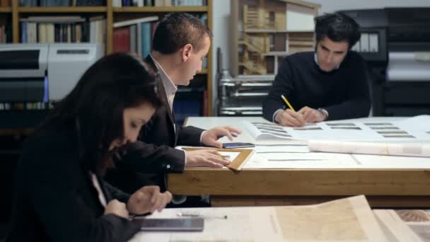 Три архитектора за работой с калькуляторами и печатными проектами: совместная работа — стоковое видео