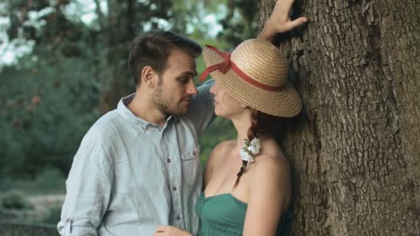 Young couple in love kissing near a tree: date, outdoor, kiss, partners — Stockvideo