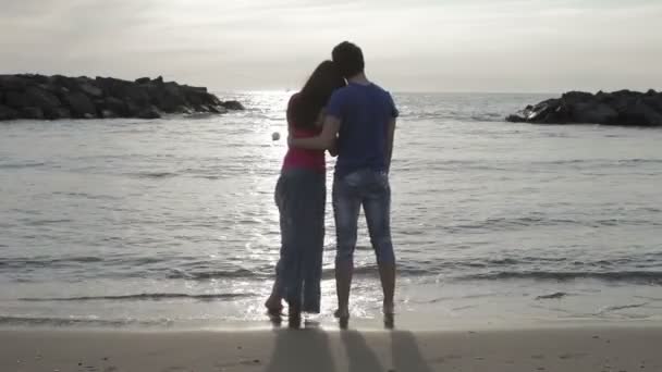 Una pareja amorosa sentados juntos en la arena, admirando