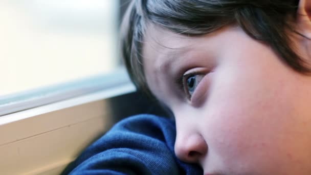 Mooi kind verveeld en nadenkend op zoek door raam — Stockvideo