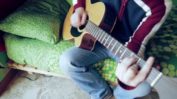 Boy plays the acoustic guitar on the bed in the morning — Stockvideo