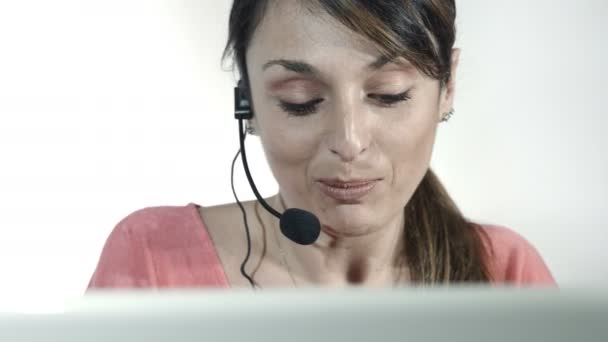 Jovem que trabalha em um call center com computador e fone de ouvido — Vídeo de Stock