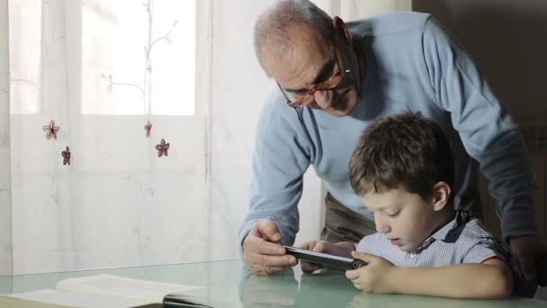 Дедушка учится у внука, как пользоваться планшетом для серфинга в Интернете — стоковое видео