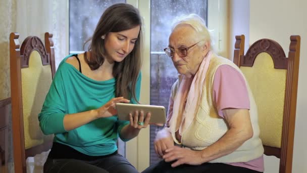 Young woman showing tablet to elderly woman — Stockvideo