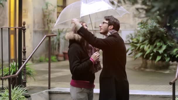 Första kyssen - en man kysser en kvinna under ett paraply i regnet — Stockvideo